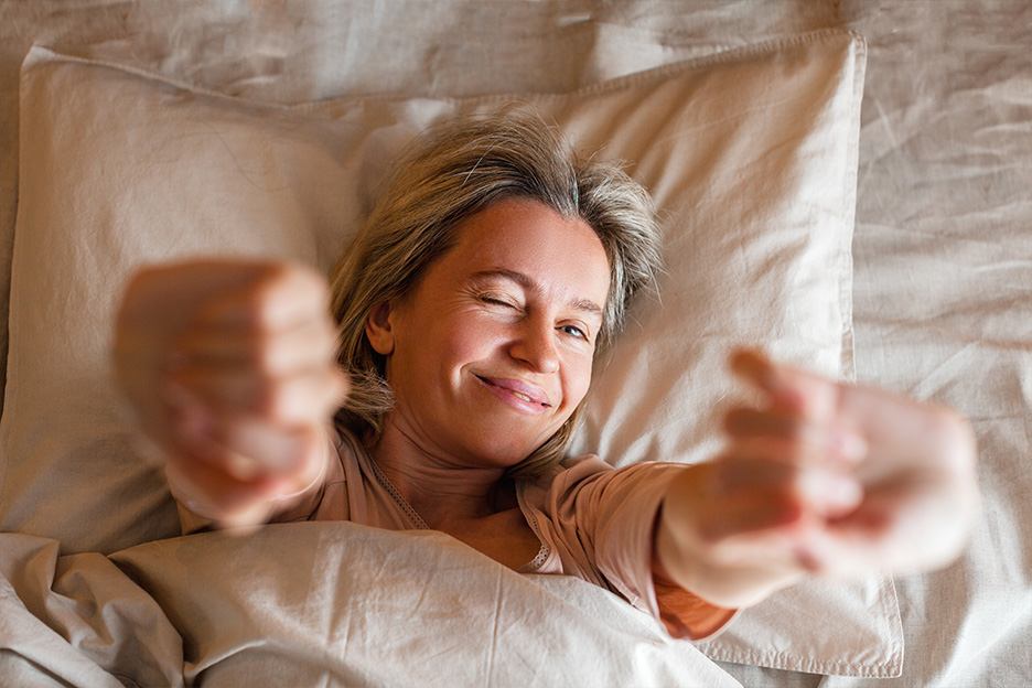 Femme qui se réveille reposée et heureuse d'avoir surmonté ses troubles du sommeil grâce à la mélatonine.